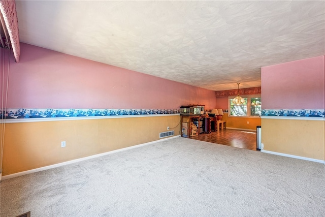 interior space featuring a notable chandelier, carpet flooring, and a textured ceiling