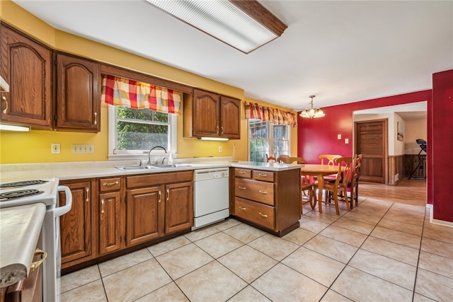 kitchen with hanging light fixtures, kitchen peninsula, sink, white appliances, and an inviting chandelier