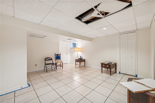 unfurnished room with a paneled ceiling and light tile patterned flooring