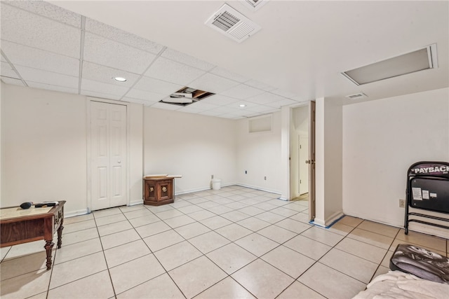 basement with light tile patterned floors and a paneled ceiling