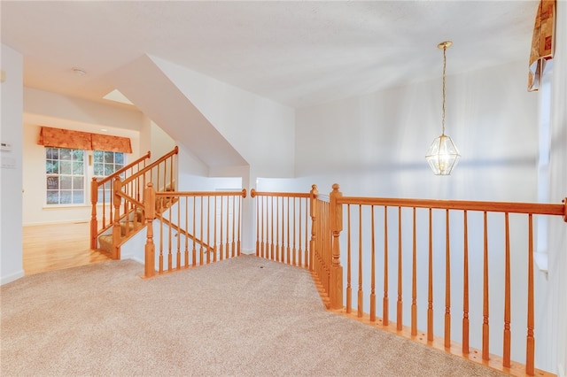 hallway featuring light colored carpet and an inviting chandelier