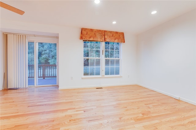 spare room featuring ceiling fan, light hardwood / wood-style flooring, and a wealth of natural light