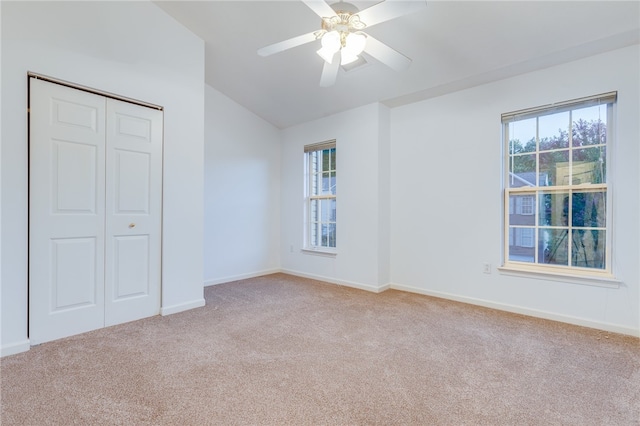 unfurnished bedroom with vaulted ceiling, ceiling fan, a closet, and light colored carpet