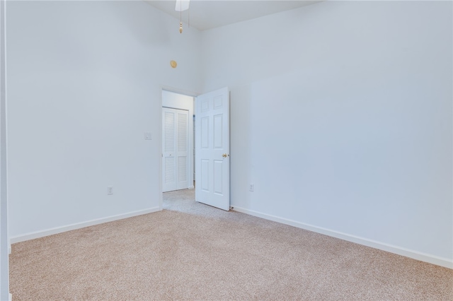 carpeted spare room featuring a towering ceiling