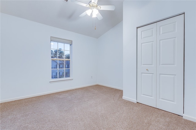 unfurnished bedroom featuring lofted ceiling, a closet, light colored carpet, and ceiling fan