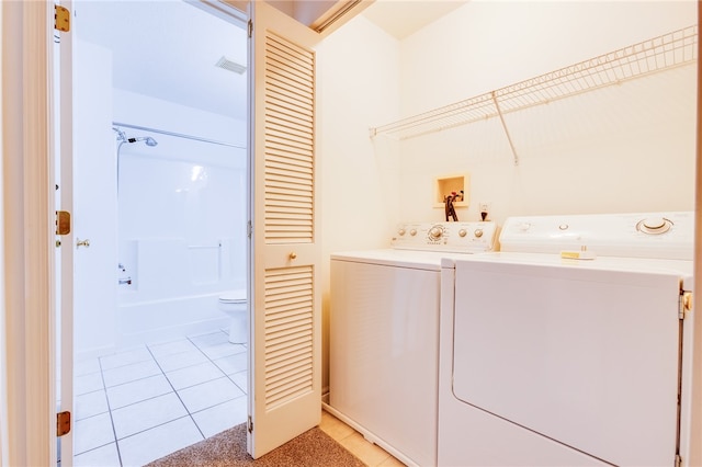 clothes washing area featuring washing machine and clothes dryer and light tile patterned floors