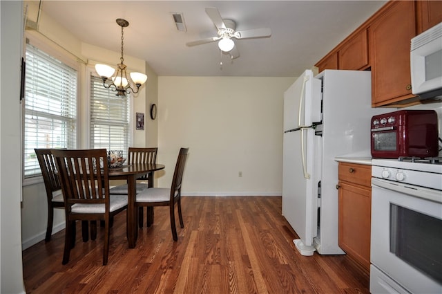 kitchen with ceiling fan with notable chandelier, hanging light fixtures, dark hardwood / wood-style flooring, and white appliances