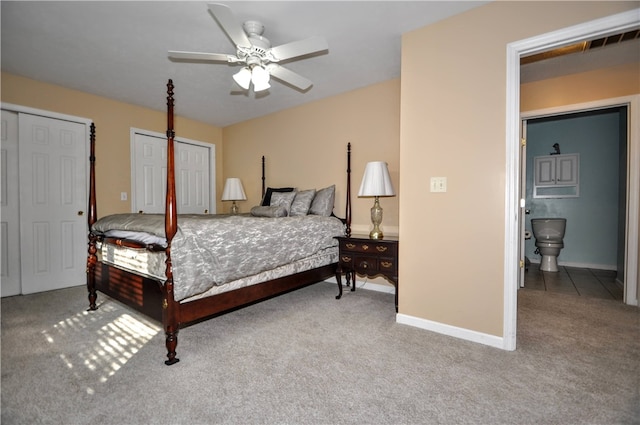 bedroom with ceiling fan, multiple closets, ensuite bath, and carpet flooring