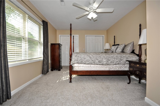 carpeted bedroom featuring multiple closets and ceiling fan