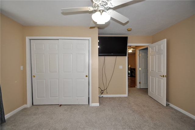 unfurnished bedroom featuring light carpet, a closet, and ceiling fan