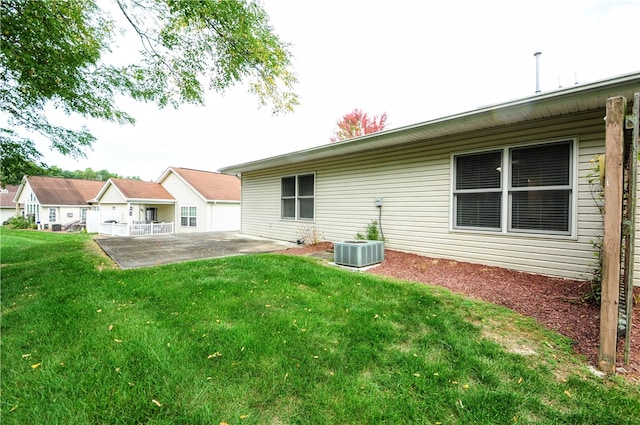 rear view of property with a patio, central AC, and a yard