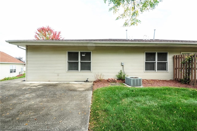 rear view of property with cooling unit, a yard, and a patio area