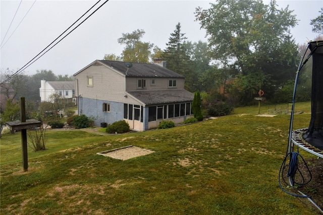 view of yard with a trampoline and a sunroom