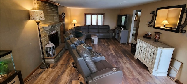 living room featuring dark hardwood / wood-style floors and a stone fireplace