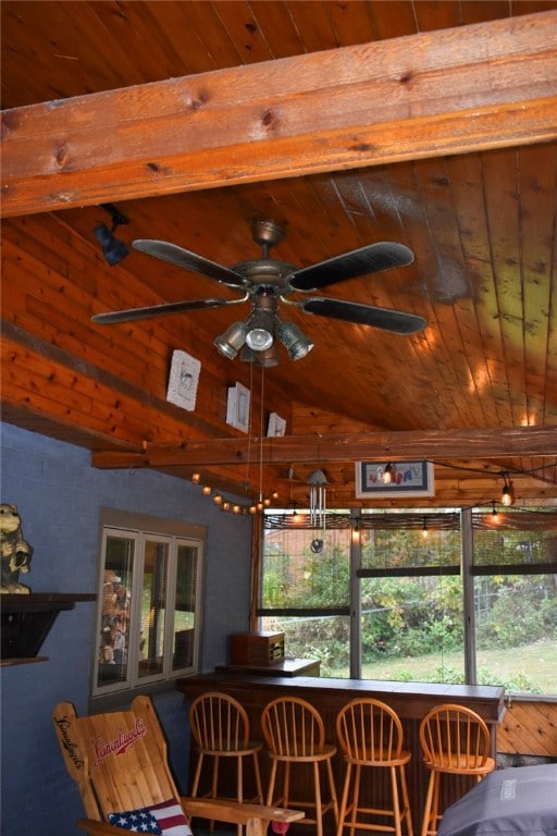 dining space featuring vaulted ceiling, wood walls, wooden ceiling, ceiling fan, and indoor bar