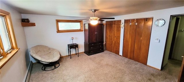 living area with ceiling fan, light carpet, and a baseboard heating unit