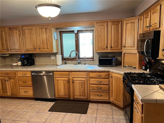 kitchen with dishwasher, tile counters, sink, decorative backsplash, and black range with gas stovetop