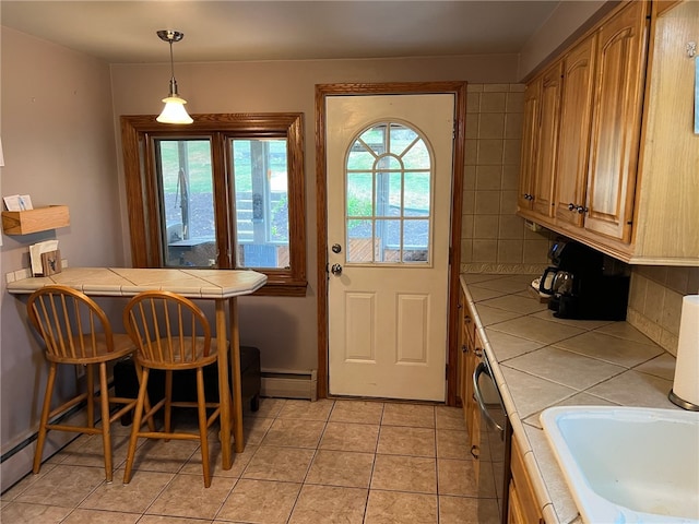 kitchen featuring pendant lighting, light tile patterned floors, stainless steel dishwasher, tile countertops, and a baseboard radiator