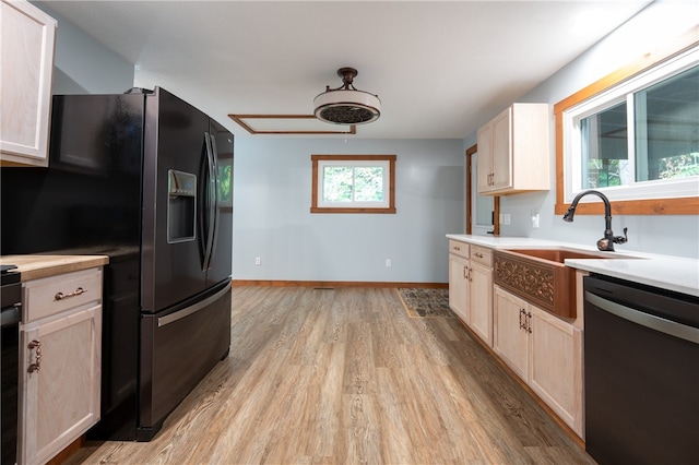 kitchen featuring dishwasher, light hardwood / wood-style flooring, sink, and black fridge with ice dispenser