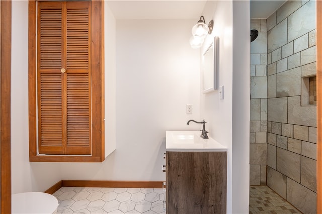 bathroom featuring a tile shower, vanity, toilet, and tile patterned floors