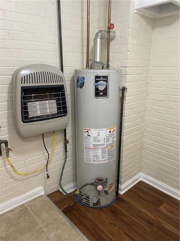 utility room featuring gas water heater and heating unit