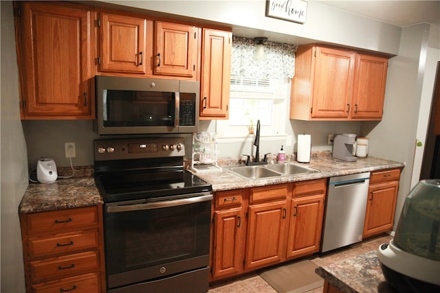 kitchen with appliances with stainless steel finishes, stone countertops, and sink