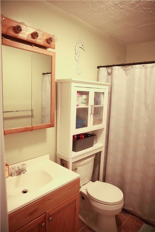 bathroom with vanity, toilet, a textured ceiling, and tile patterned floors