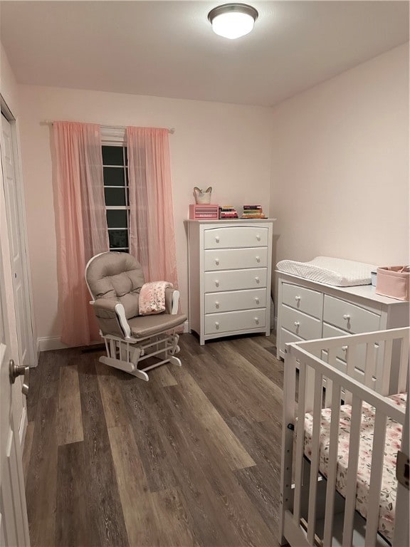 bedroom with a nursery area and dark hardwood / wood-style floors