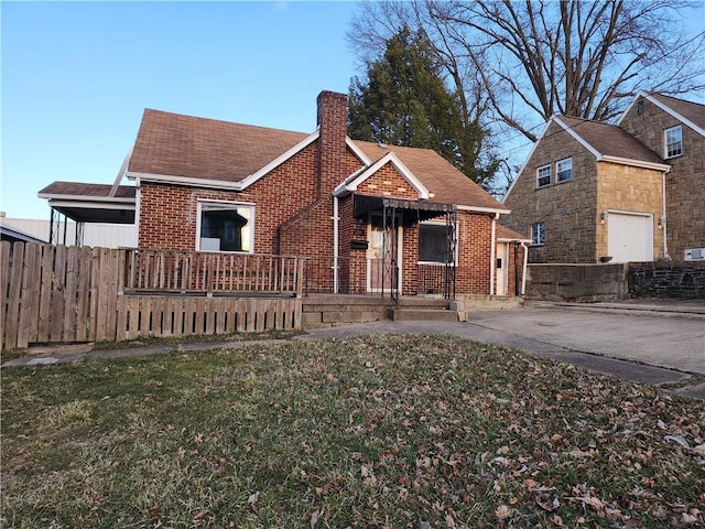 bungalow with a front yard, a chimney, fence, and brick siding