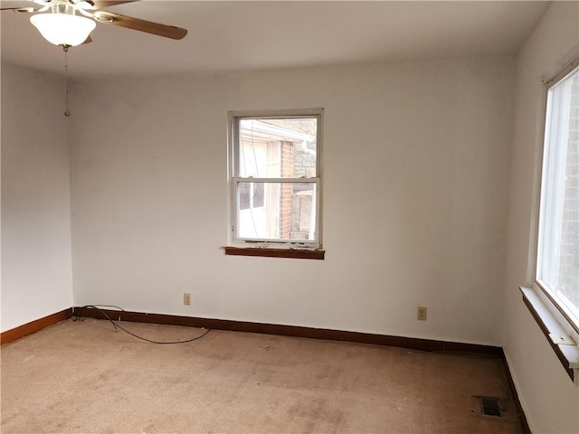 empty room with ceiling fan, carpet flooring, visible vents, and baseboards