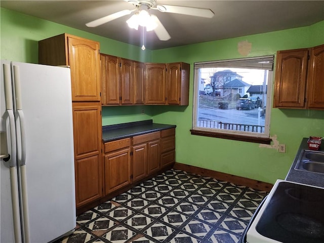 kitchen featuring electric range, white refrigerator with ice dispenser, baseboards, a ceiling fan, and dark countertops