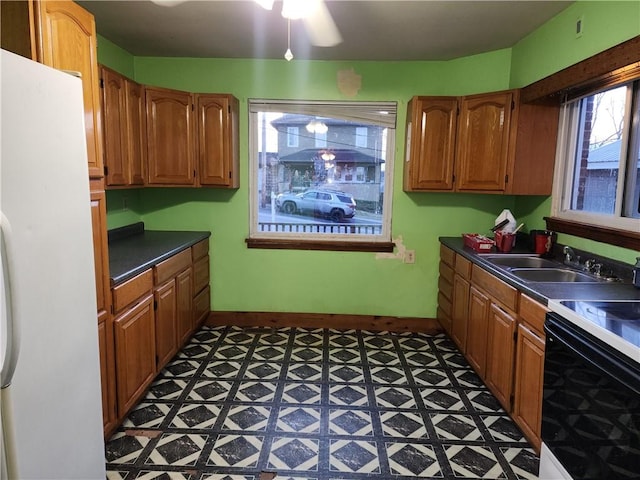 kitchen with dark countertops, freestanding refrigerator, a sink, range with electric cooktop, and tile patterned floors