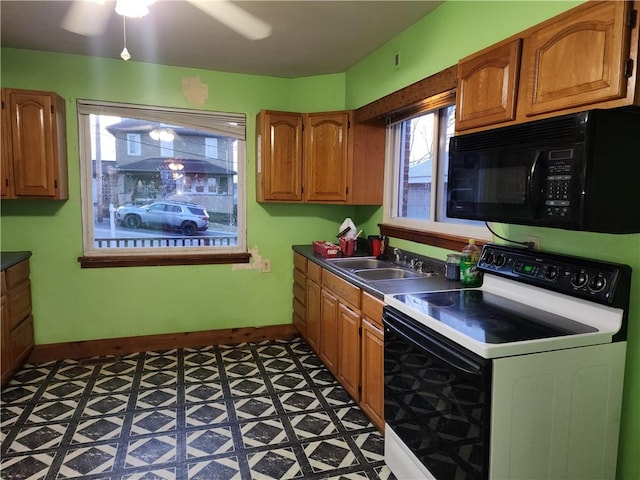 kitchen featuring baseboards, black microwave, a sink, and range with electric stovetop