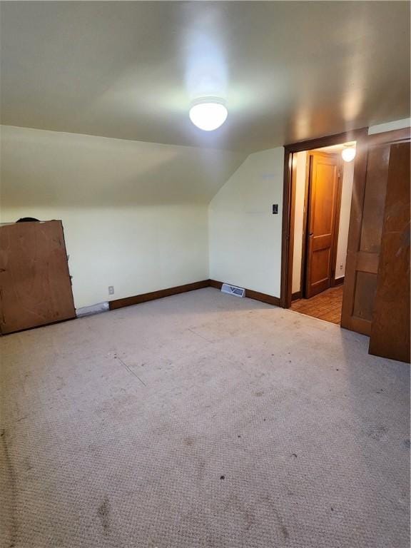 bonus room featuring light carpet, baseboards, visible vents, and lofted ceiling