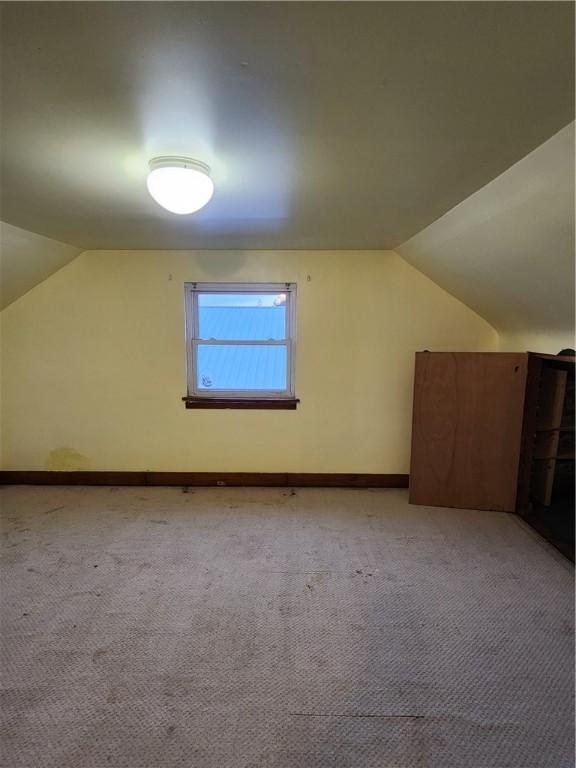 bonus room with vaulted ceiling, baseboards, and light colored carpet