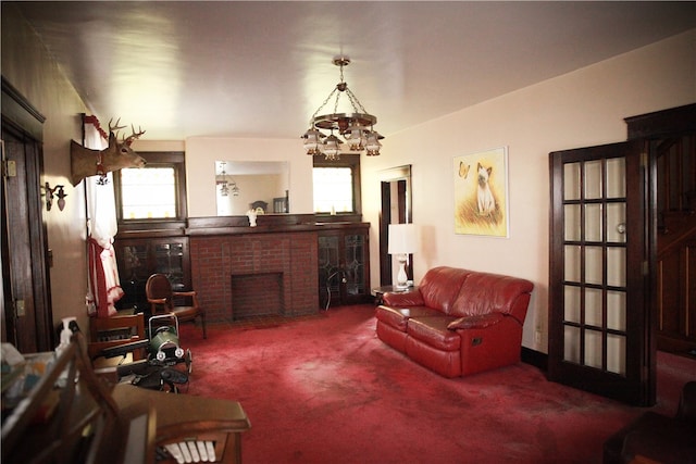 living room featuring a notable chandelier, a brick fireplace, and carpet flooring