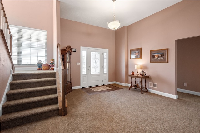 foyer entrance featuring plenty of natural light, a high ceiling, and carpet flooring