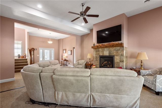 living room with ceiling fan, light colored carpet, and a tile fireplace