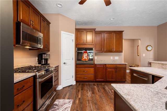 kitchen featuring light stone countertops, ceiling fan, dark hardwood / wood-style floors, stainless steel appliances, and a textured ceiling