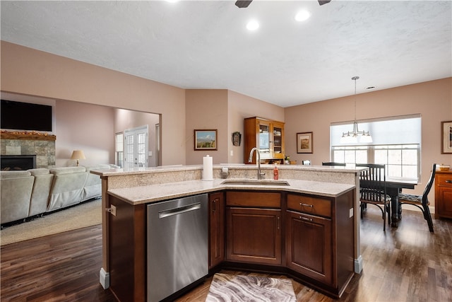 kitchen featuring pendant lighting, sink, dishwasher, dark hardwood / wood-style floors, and a fireplace