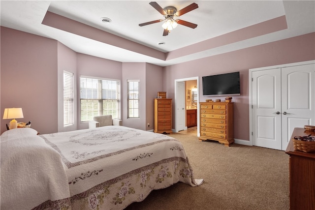 carpeted bedroom featuring ceiling fan, a raised ceiling, and connected bathroom