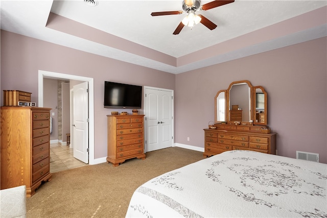 carpeted bedroom with ceiling fan and a raised ceiling