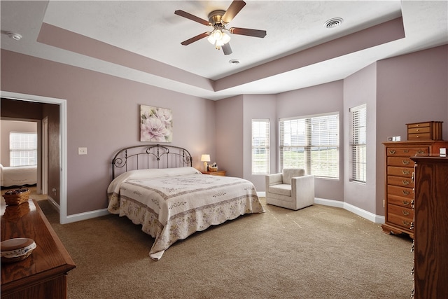 bedroom featuring a tray ceiling, carpet, and ceiling fan