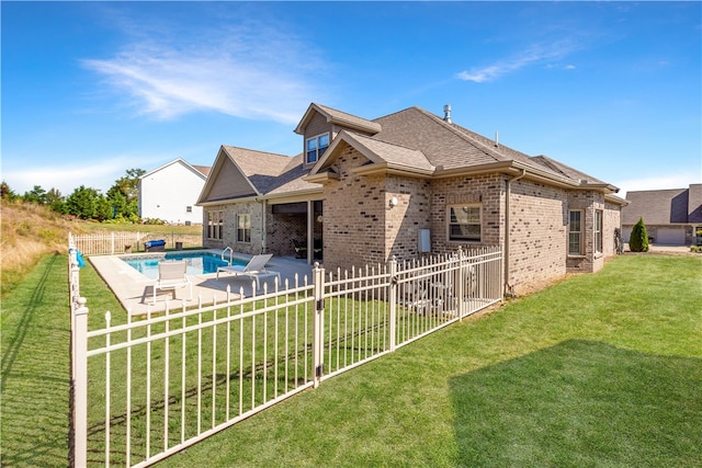 rear view of house featuring a fenced in pool, a lawn, and a patio area