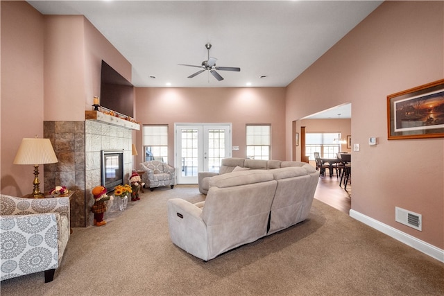 carpeted living room featuring ceiling fan and a tiled fireplace