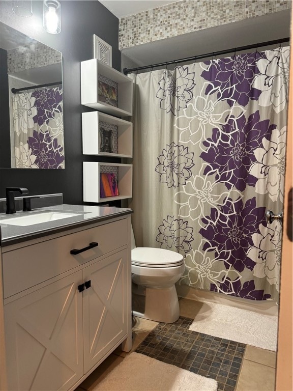 bathroom with walk in shower, vanity, tile patterned flooring, and toilet