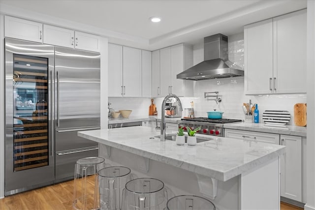 kitchen featuring wall chimney exhaust hood, white cabinets, and appliances with stainless steel finishes