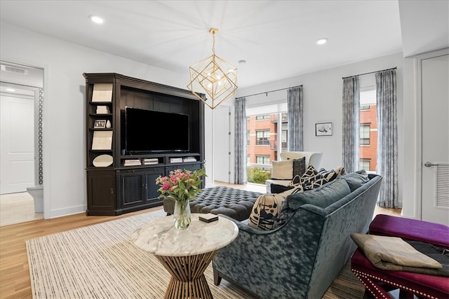 living room featuring a notable chandelier and light wood-type flooring