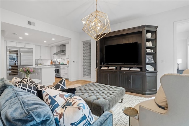 living room featuring light hardwood / wood-style flooring, a chandelier, and sink