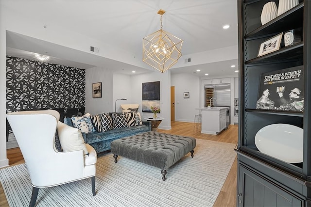 living room with light hardwood / wood-style floors and an inviting chandelier